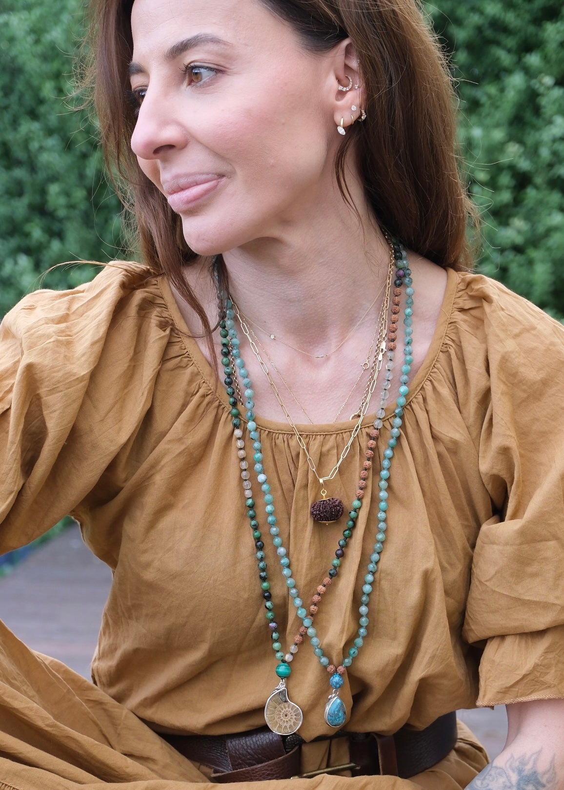 Woman wearing Ammonite mala necklace pendant with green and gold beads
