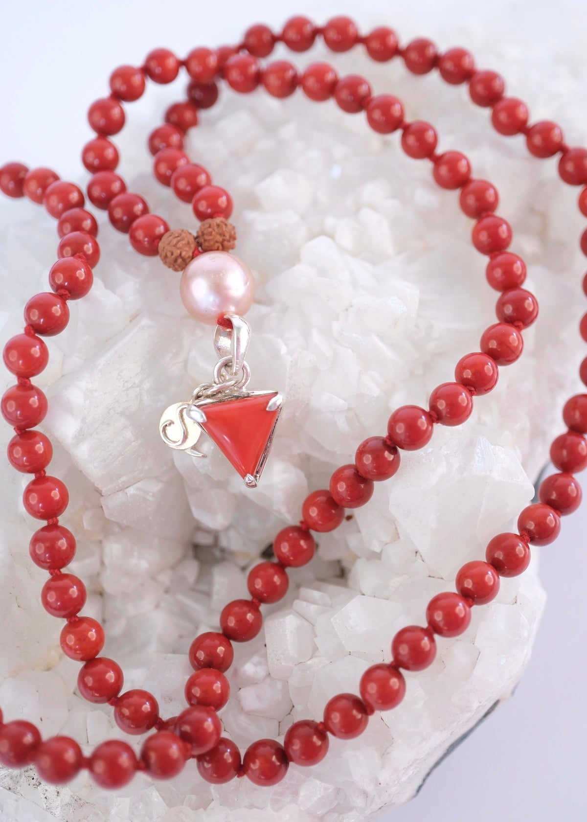 Handcrafted red coral Mars mala laid full length with triangular Moonga pendant and Pink Akoya Pearl