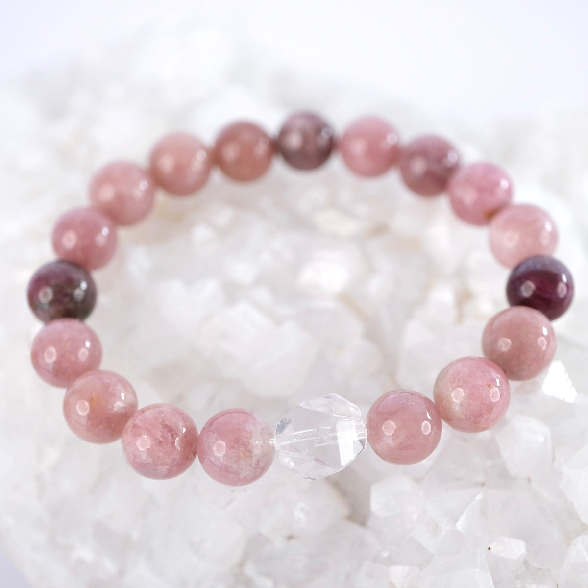 Close view of rose and plum pink tourmaline beads and a faceted clear quartz on the Karuna bracelet.