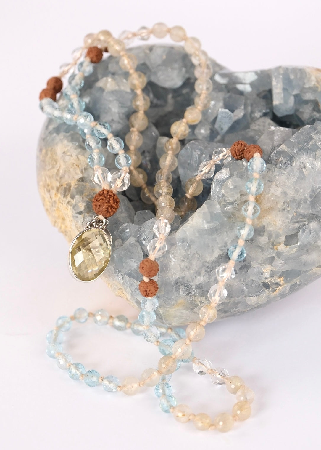 Prashanti mala of profound peace with faceted blue topaz, golden rutilated quartz, Herkimer, Rudraksha, and a lemon quartz pendant in sterling silver.