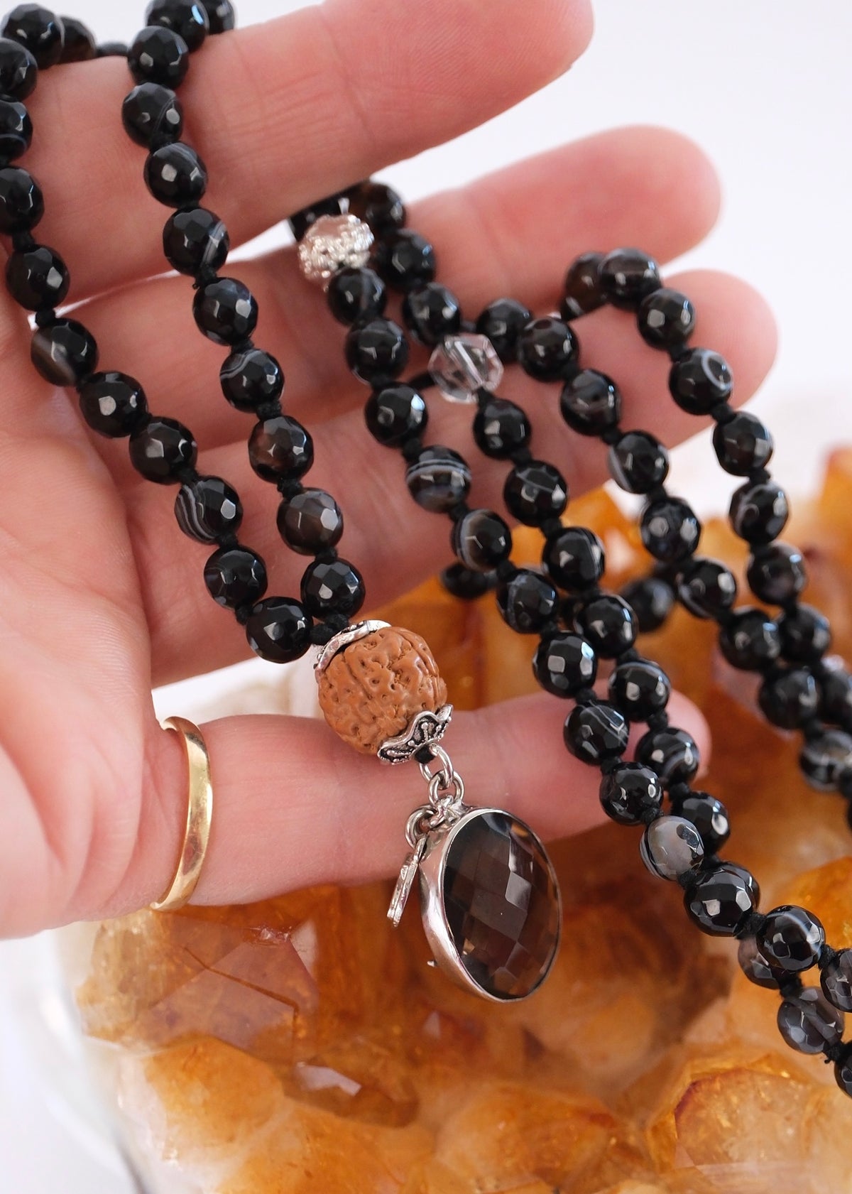 Hand holding black
Onyx Mala necklace for men near a citrine crystal