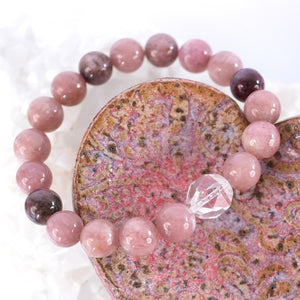 Close view of rose and plum pink tourmaline beads and a faceted clear quartz on the Karuna bracelet.