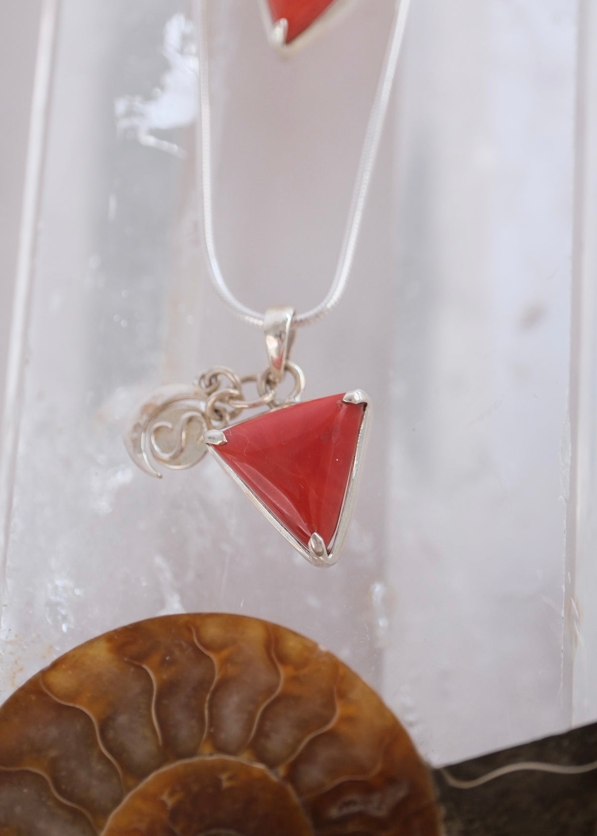 Close view of a deep red Italian coral Mars pendant with crescent moon and S Shivoham charms.