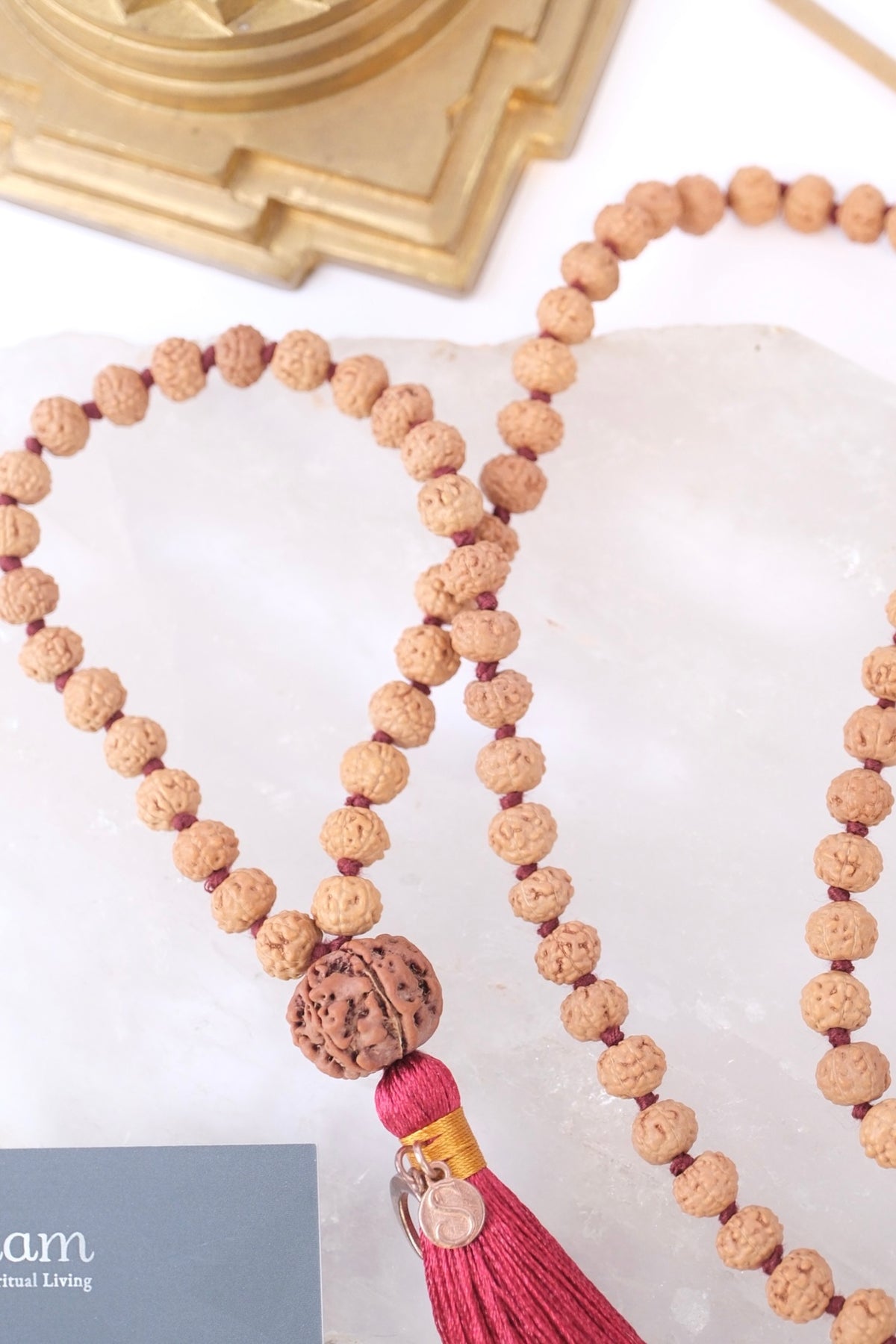 Necklace with wooden beads and a pink tassel on a white surface