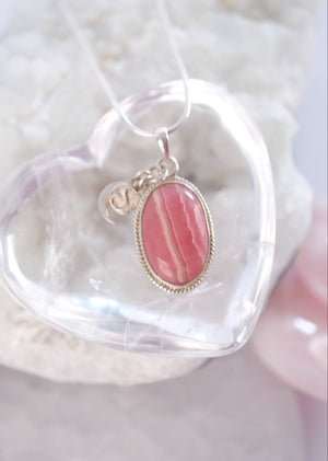 Close view of a beautifully banded rhodochrosite cabochon in a rope edged silver setting.