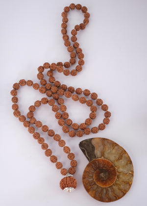 Shivoham Premium collector's Rudraksha japa mala for courage, wisdom, focus, and clarity, finished with sterling silver caps and charms. Authentic Nepal Rudraksha mala resting on clear quartz crystal