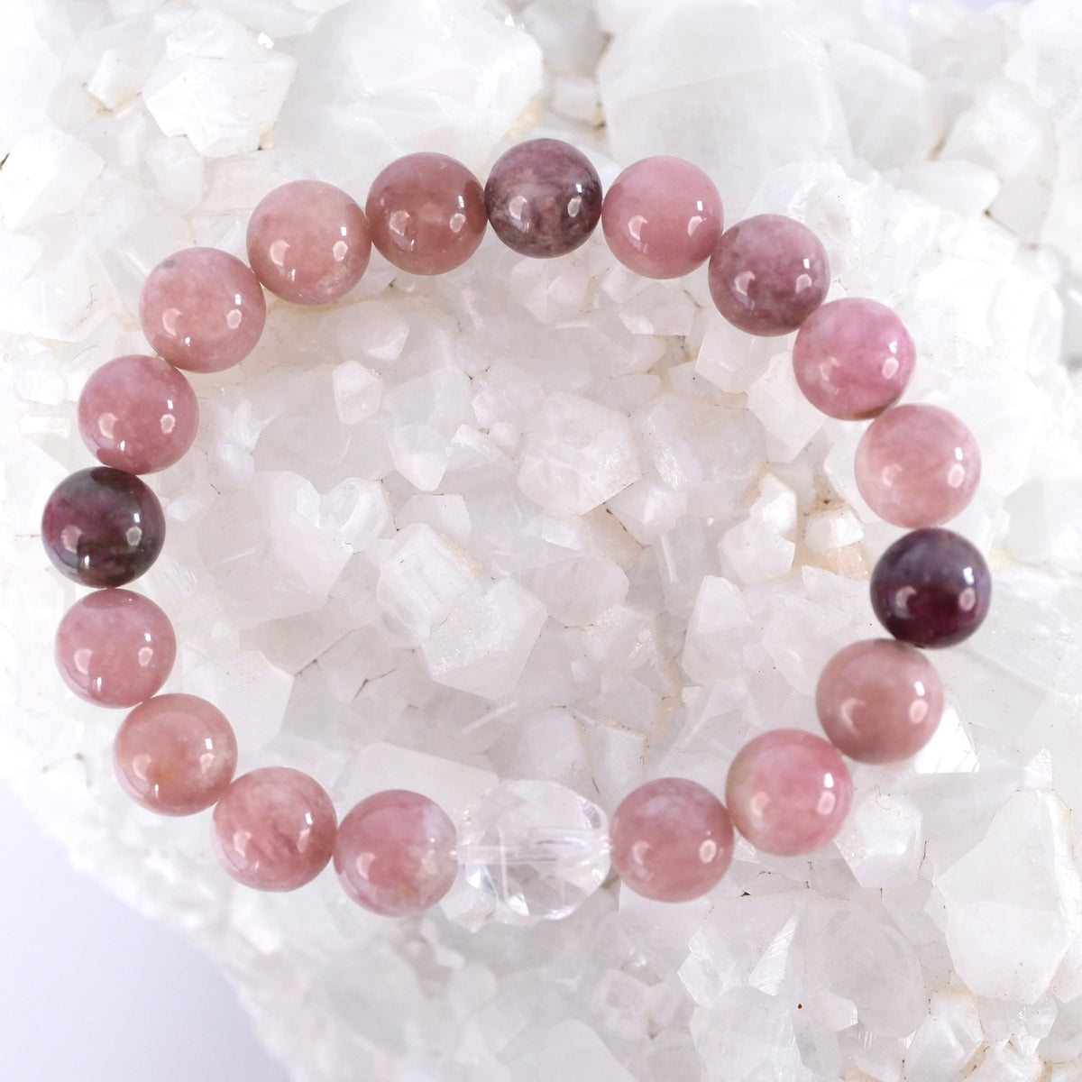 Tender pink tourmaline bracelet resting on quartz, the stone of the compassionate heart.