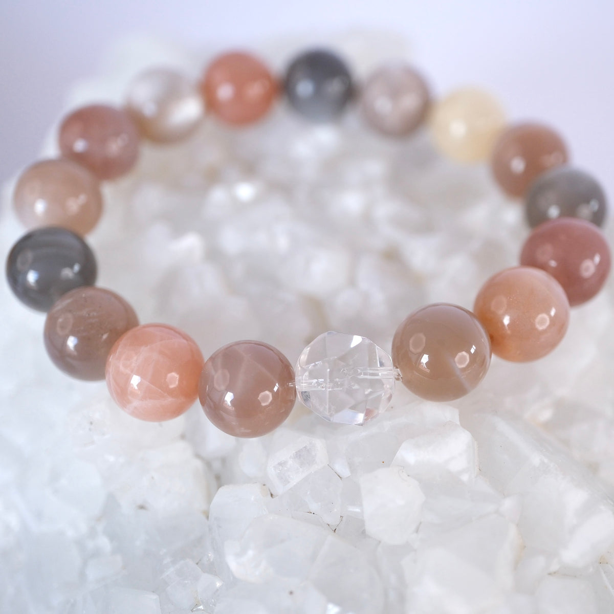 Close view of peach, grey, and cream 12mm moonstone beads and a Herkimer diamond on the Chandra Kala bracelet.