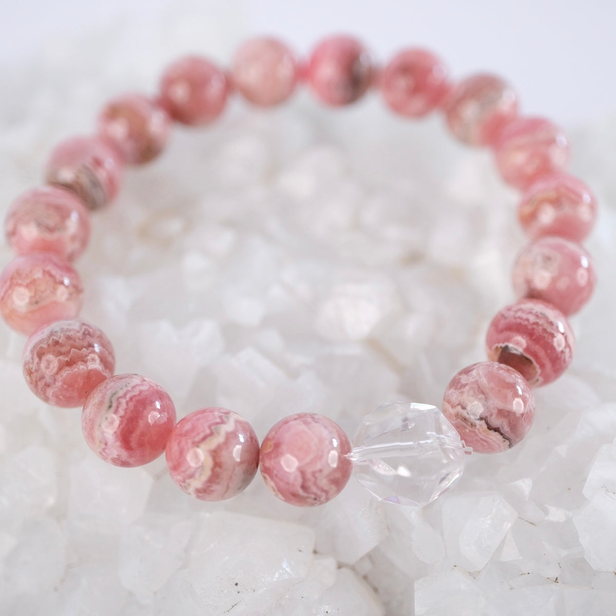 Close view of AAA rhodochrosite beads and a clear Herkimer diamond on the Maha Prana Anand bracelet.