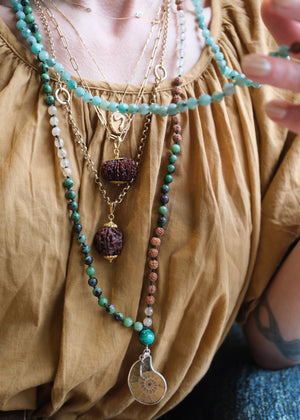 Handcrafted seer’s mala with ammonite pendant, ruby zoisite, golden rutilated quartz, malachite and Rudraksha. Blessed by the Ganga. Magic for sages and manifestation.