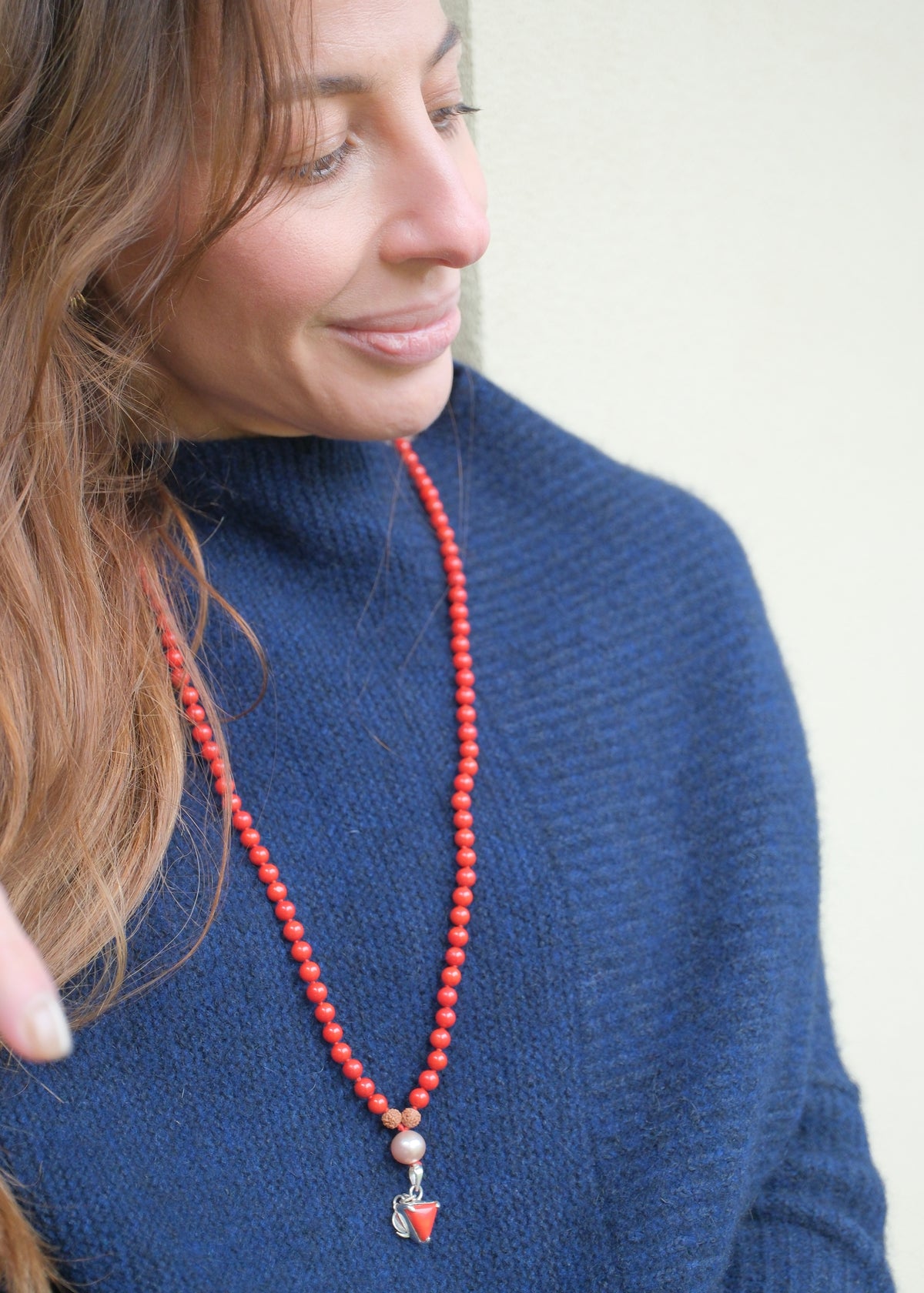 Red coral Mars mala styled on a model in blue, the Moonga pendant on show