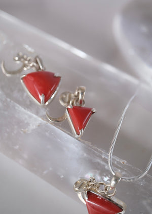 Close view of a deep red Italian coral Mars pendant with crescent moon and S Shivoham charms.