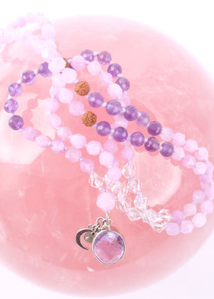 Purple beaded bracelet with a silver charm on a white background