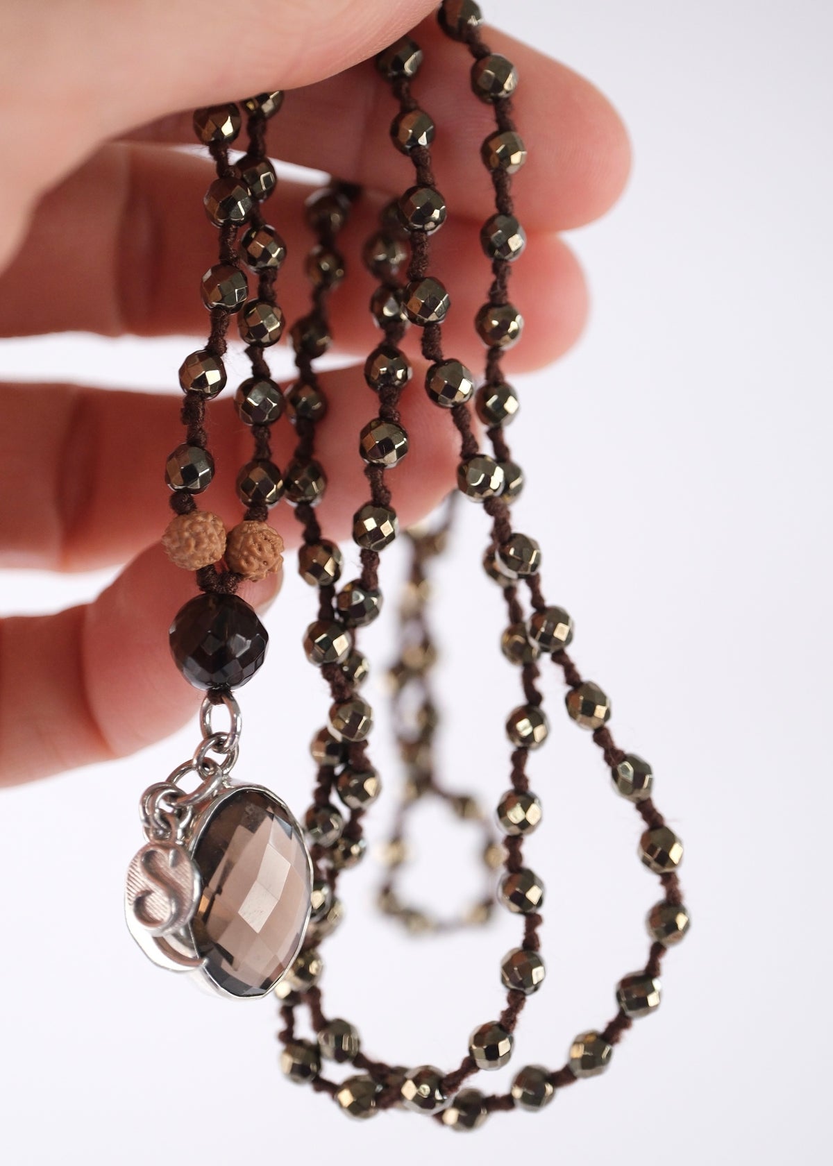 Deep grey hematite and smoky quartz prayer mala for grounding, protection, and mental clarity, a beautiful mala for men.
Close view of the faceted smoky quartz pendant with crescent moon and S charms