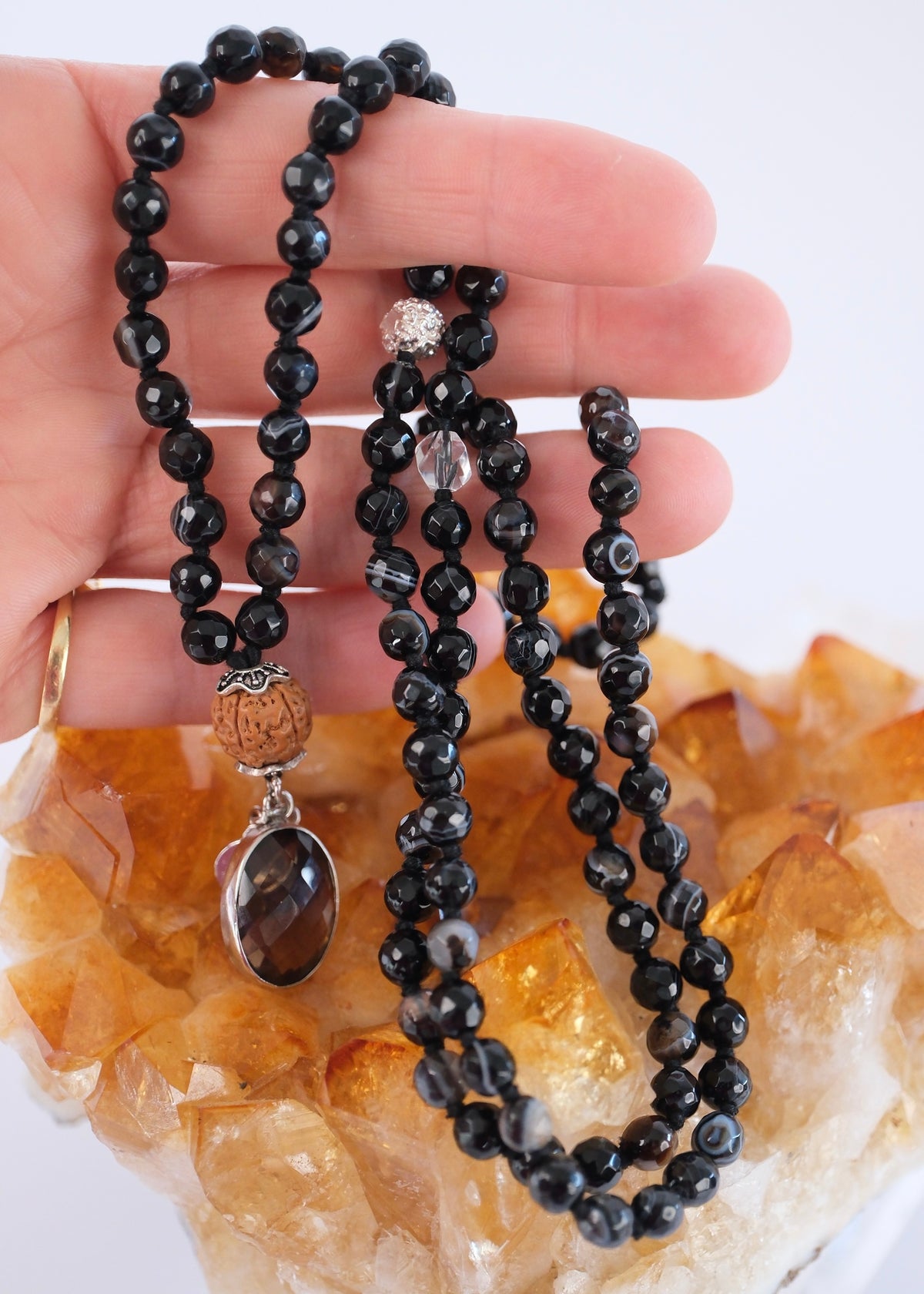 Faceted black onyx mala with natural white banding, resting on citrine, the thunderbolt of power.