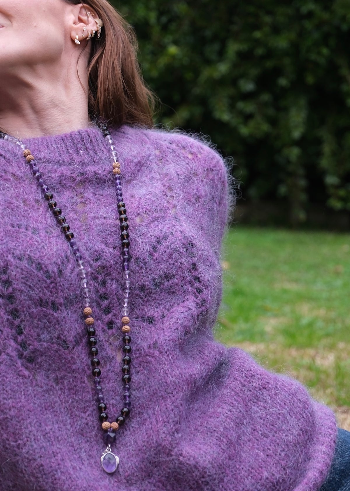 Woman wearing amethyst and smoky Quartz pendant Mala wearing a purple jumper