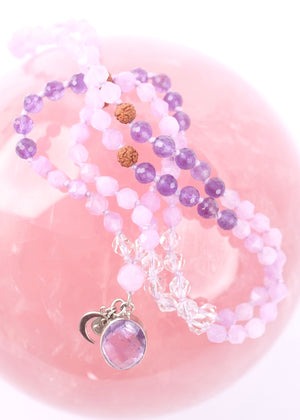 Purple beaded bracelet with a silver charm on a white background