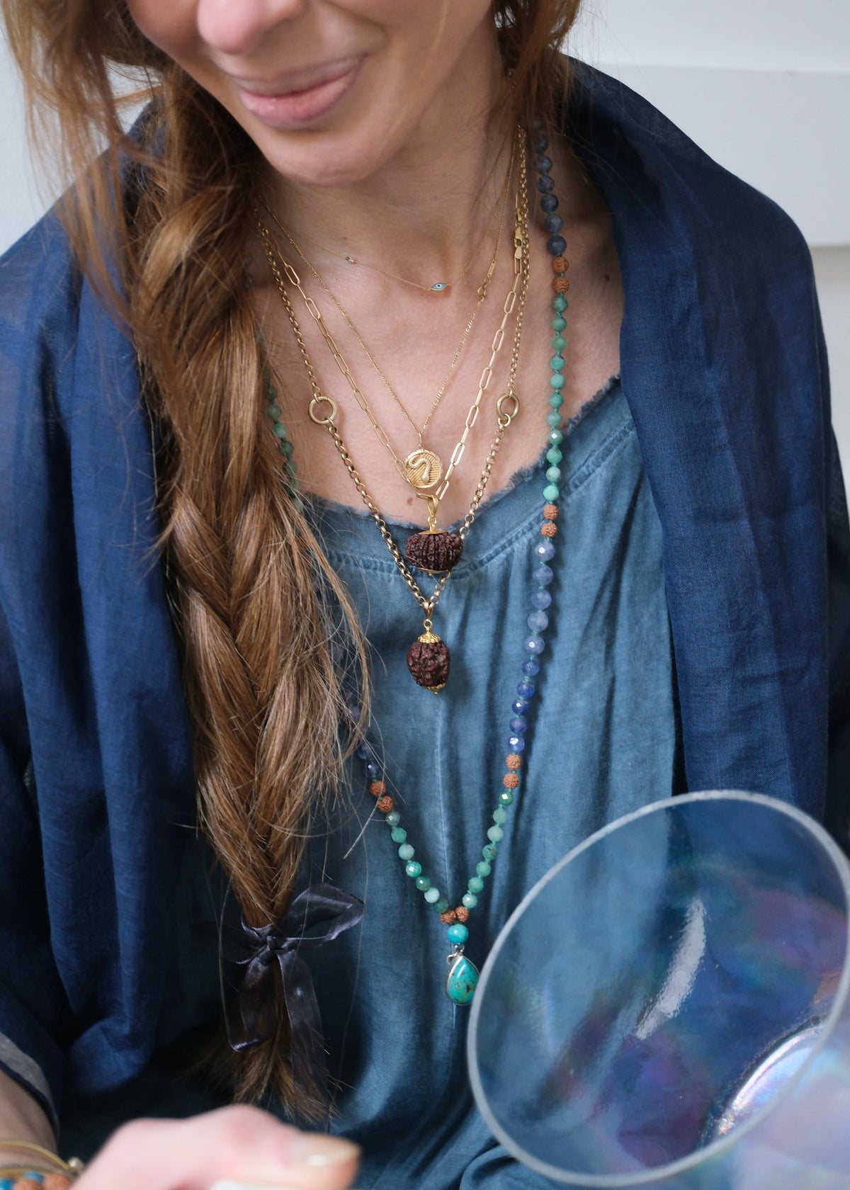 Woman in Blue wearing Shivoham Mala with Persian turquoise guru bead on a faceted emerald and tanzanite success mala