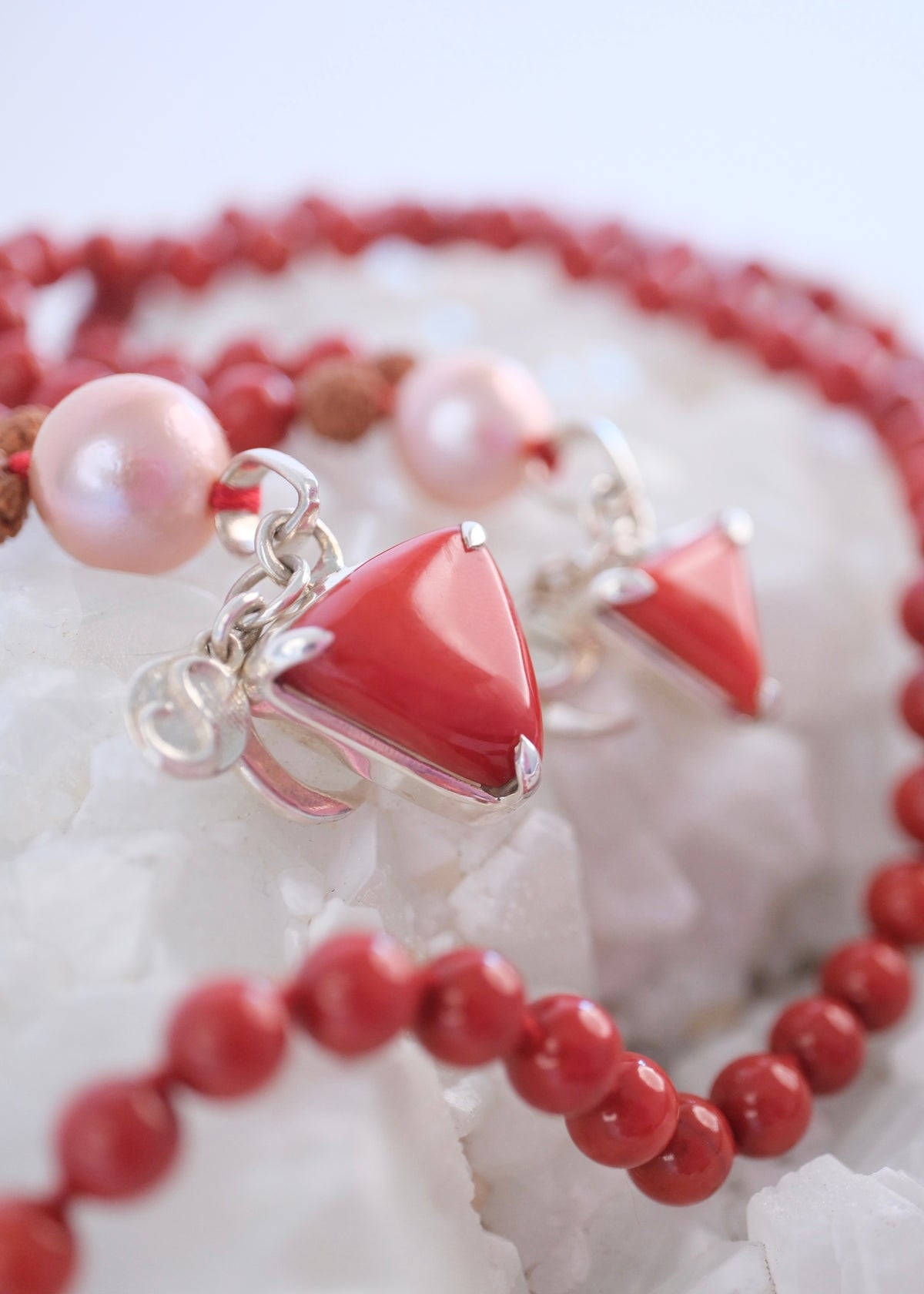 Close up of Italian red coral pendant and mala with pink pearl bead and sterling silver case