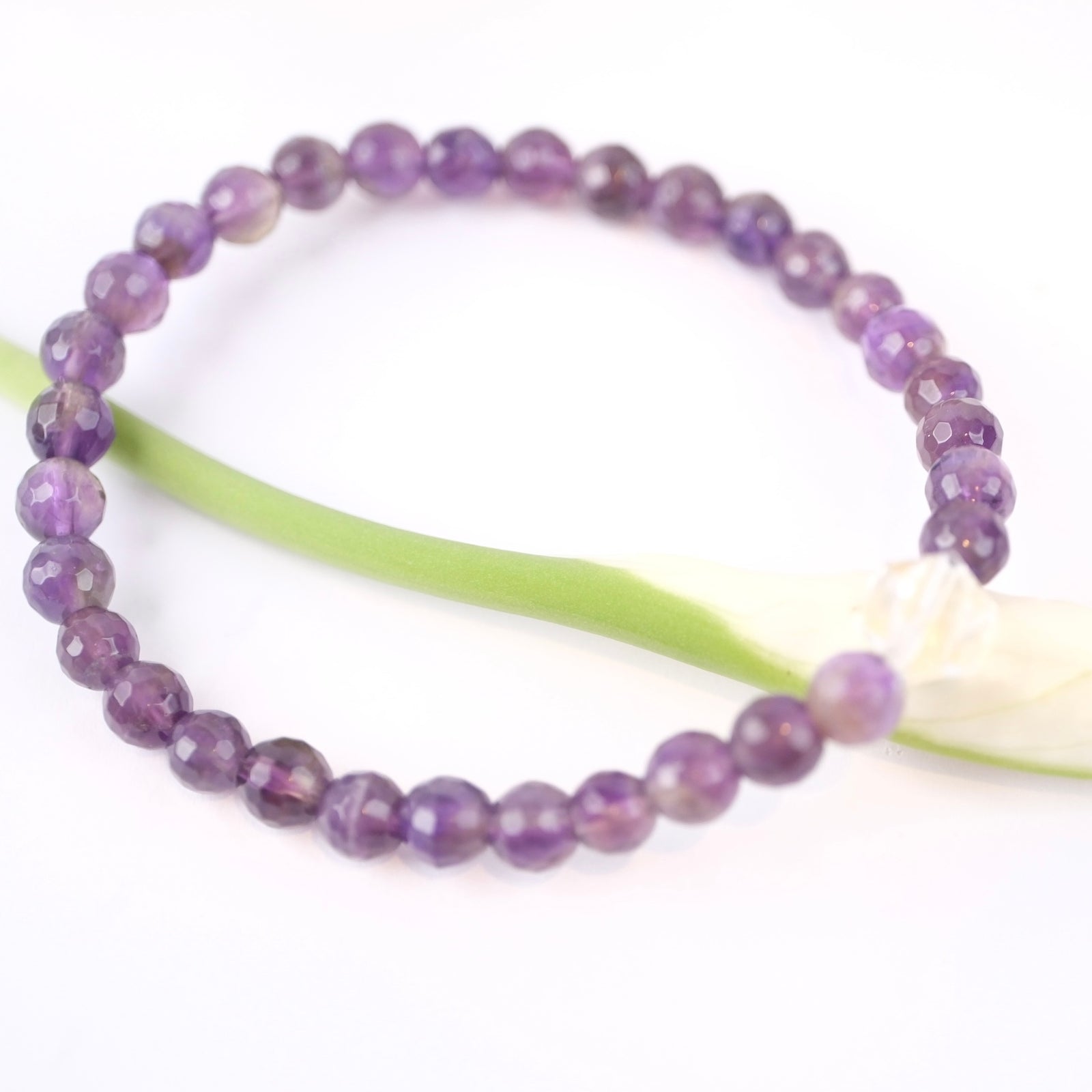 Amethyst Bracelet with 6mm faceted beads and Herkimer Diamond photographed on an peace lili bud