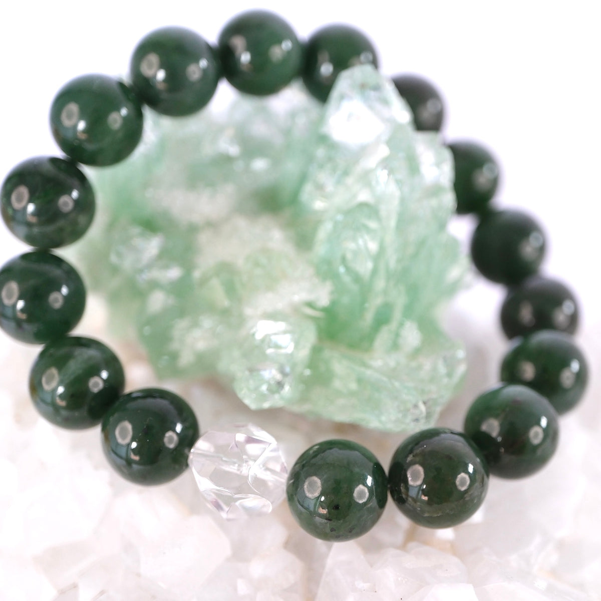 Close view of rich green 12mm jade beads and a faceted clear quartz on the Jade Buddha bracelet.