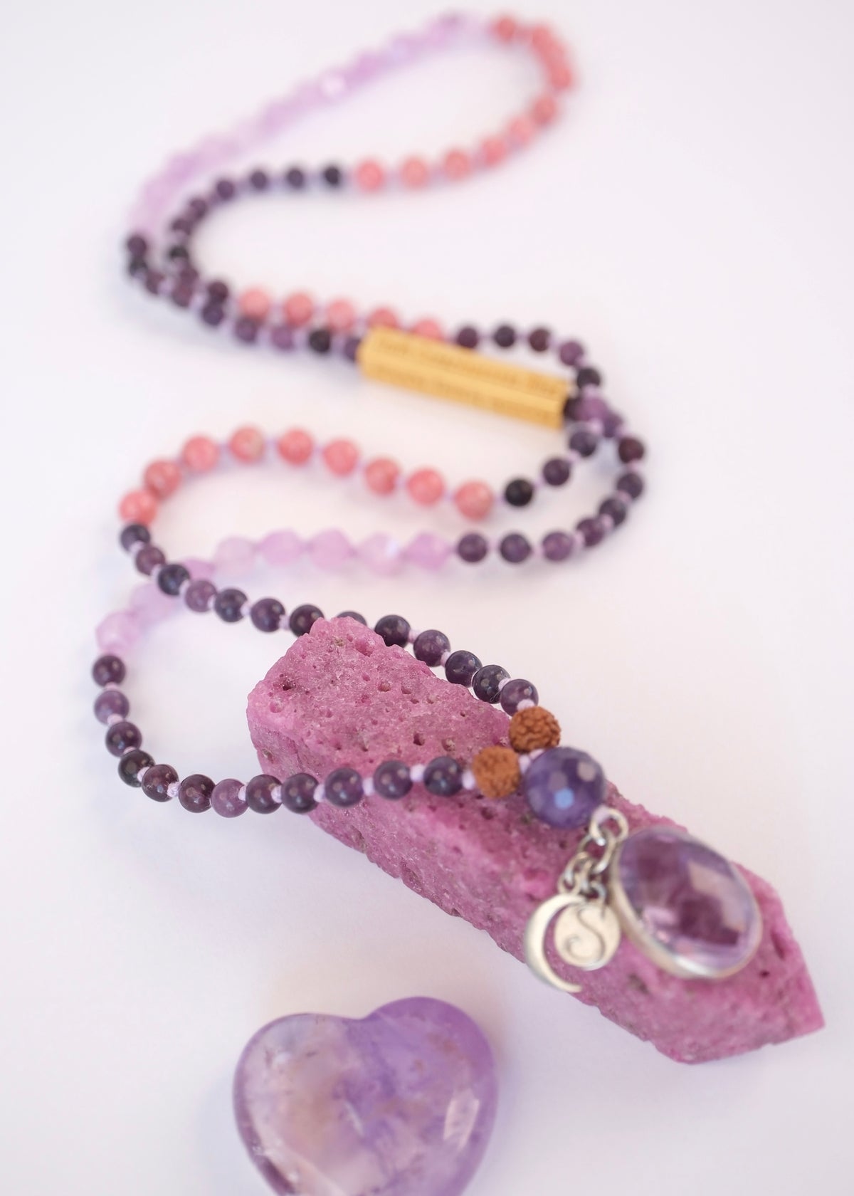Beaded necklace with a pink crystal pendant on a white background