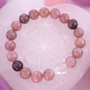 Close view of rose and plum pink tourmaline beads and a faceted clear quartz on the Karuna bracelet.