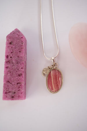 Close view of a beautifully banded rhodochrosite cabochon in a rope edged silver setting.