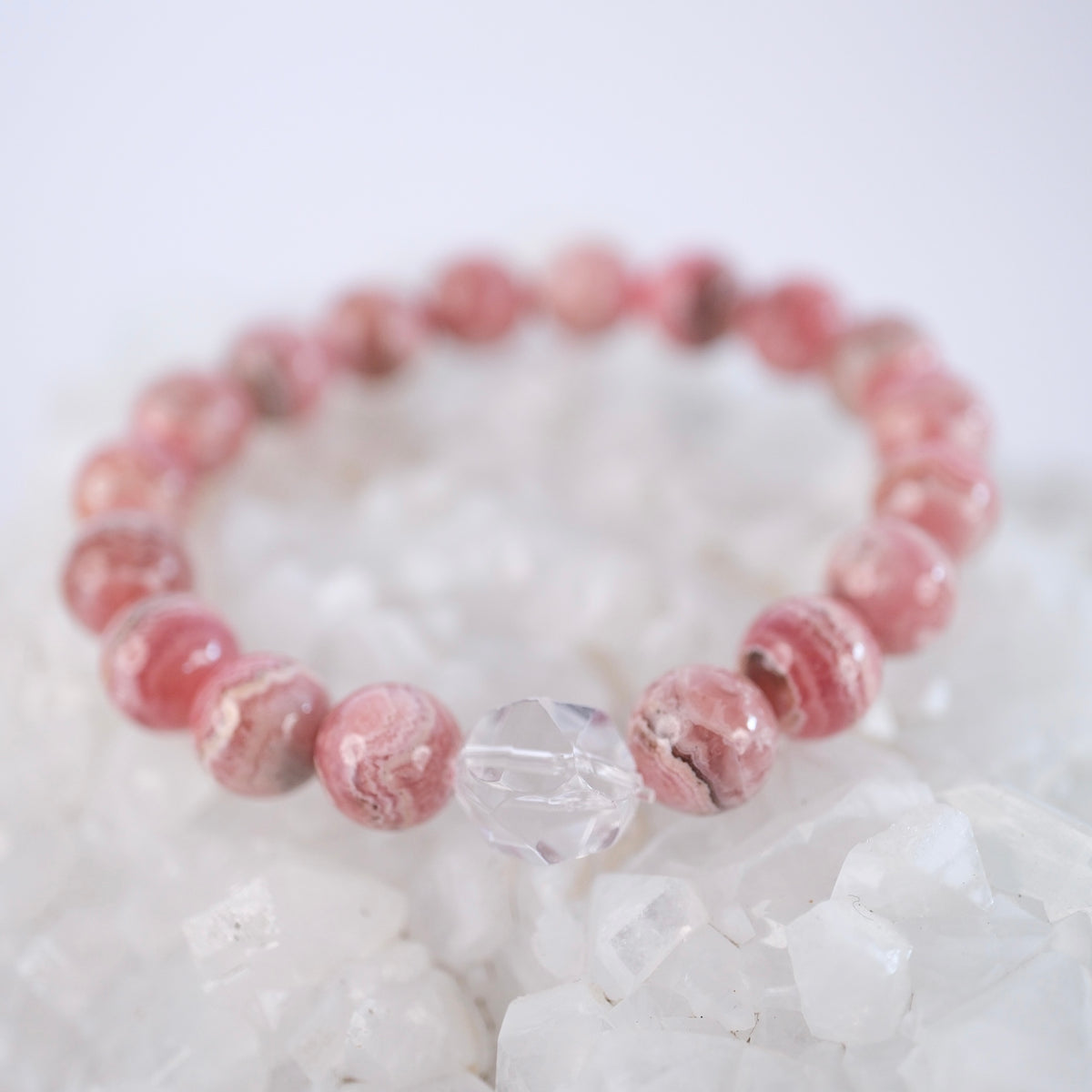 Rich pink rhodochrosite and Herkimer bracelet resting on quartz, radiant with the power of love.