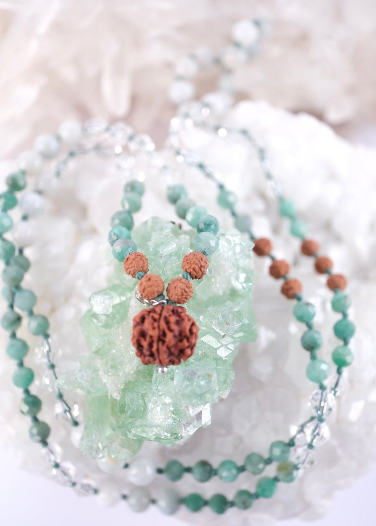 Close view of the rare small Ganesh Rudraksha guru bead capped in sterling silver on the Riddhi jade and emerald