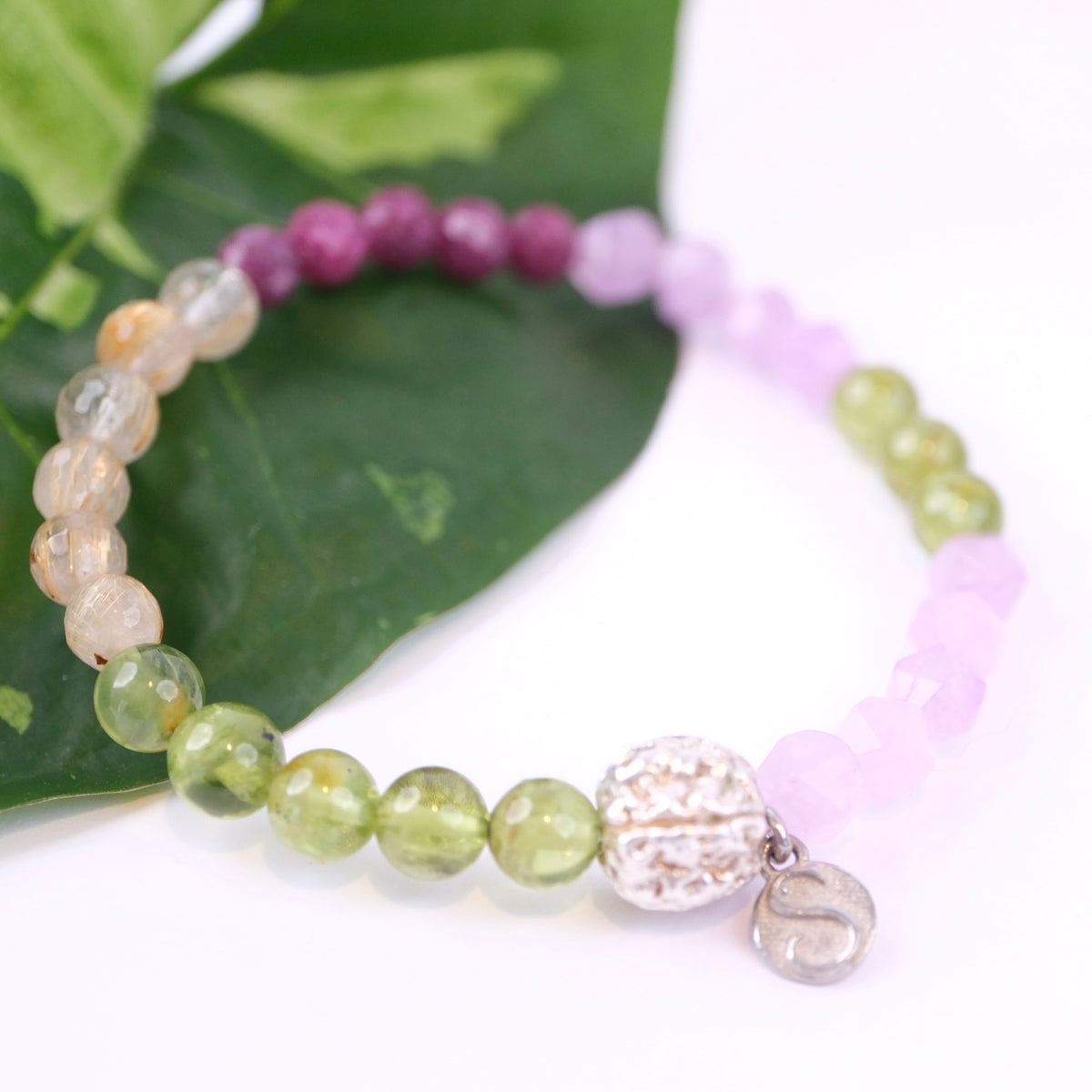 Peridot, Ruby, Lavender Quartz, Gold in Quartz with Sterling Silver bead and charm bracelet on green leaf