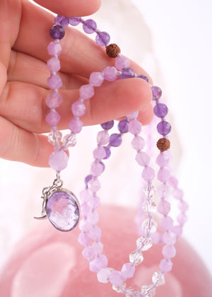 Purple beaded bracelet with a silver charm on a white background